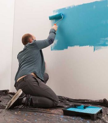 Artist decorating the boy's room with blue paint. Home during renovation, decoration and painting. Interior apartment improvement maintenance. Roller, ladder for house repair